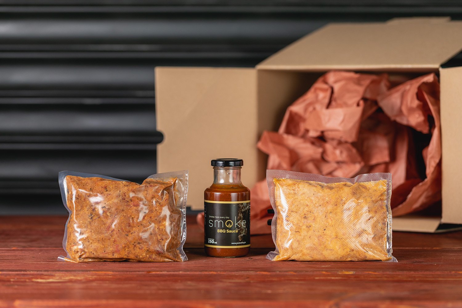 Zwei vakuumverpackte Portionen Pulled Pork im Lieferkarton mit Smoke BBQ Sauce