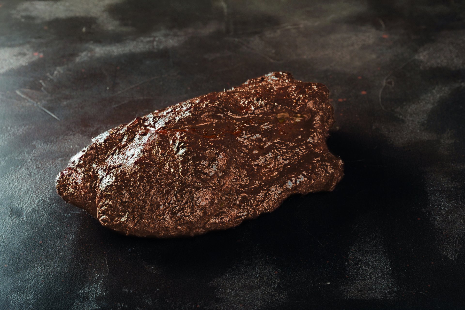 Schweinenacken von Smoke BBQ, am Stück im Smoker gegart, mit rotbrauner Bark auf dunklem Stein