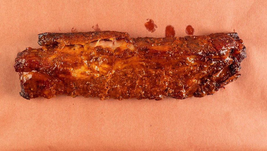 Baby Back Ribs mit BBQ-Glasur auf Butcher-Paper, bereit zum Einwickeln und Aufwärmen
